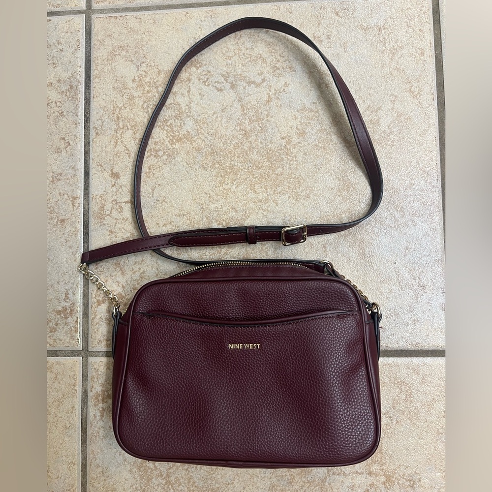 Like new Nine West Burundy Crossbody camera Bag has three pockets & gold chain